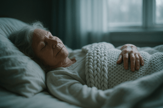 senior lying in bed beneath a thick, white weighted blanket