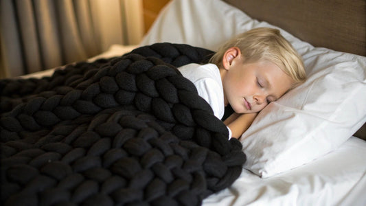 toddler sleeping under knitted weighted blanket