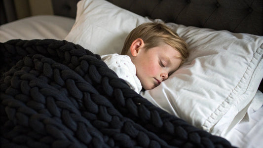 young kid sleeping with black knitted weighted blanket